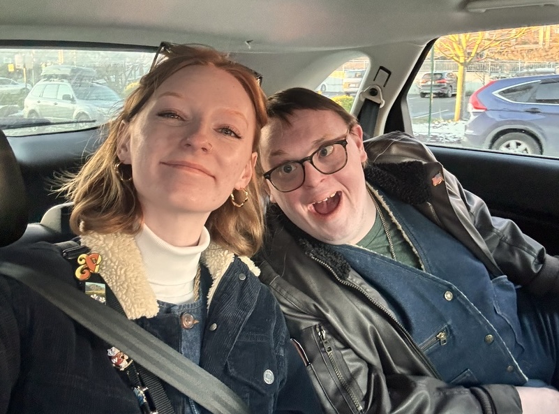Hailey and her brother Adam in a car smiling at the camera